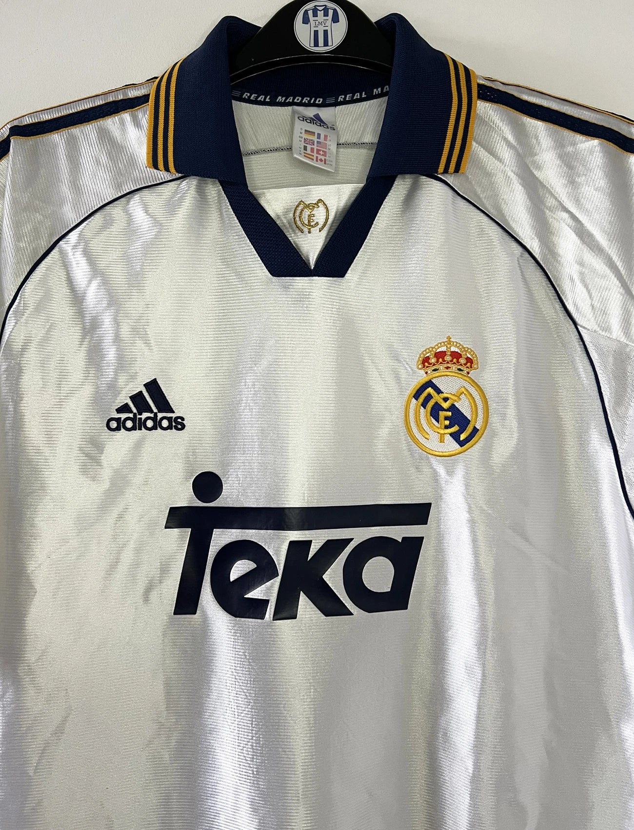 Maillot de foot vintage domicile blanc du Real Madrid de la saison 1998/1999. On peut retrouver l'équipementier Adidas et le sponsor Teka. Il s'agit d'un maillot authentique d'époque.