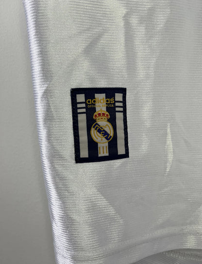 Maillot de foot vintage domicile blanc du Real Madrid de la saison 1998/1999. On peut retrouver l'équipementier Adidas et le sponsor Teka. Il s'agit d'un maillot authentique d'époque.