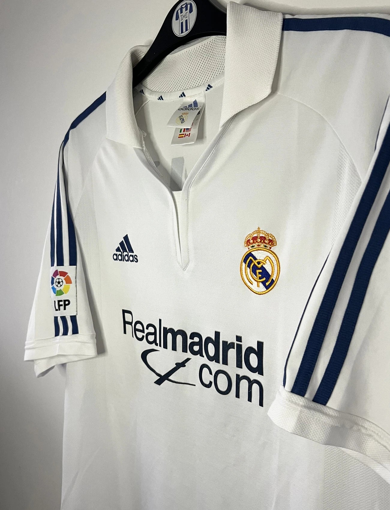 Maillot de foot vintage domicile du real madrid de la saison 2001-2002. Le maillot est de couleur blanc et noir. On peut retrouver l'équipementier adidas et le sponsor Real Madrid.com. Le maillot est floqué du numéro 5 Zinedine Zidane. Il s'agit d'un maillot authentique comportant les numéros 695856