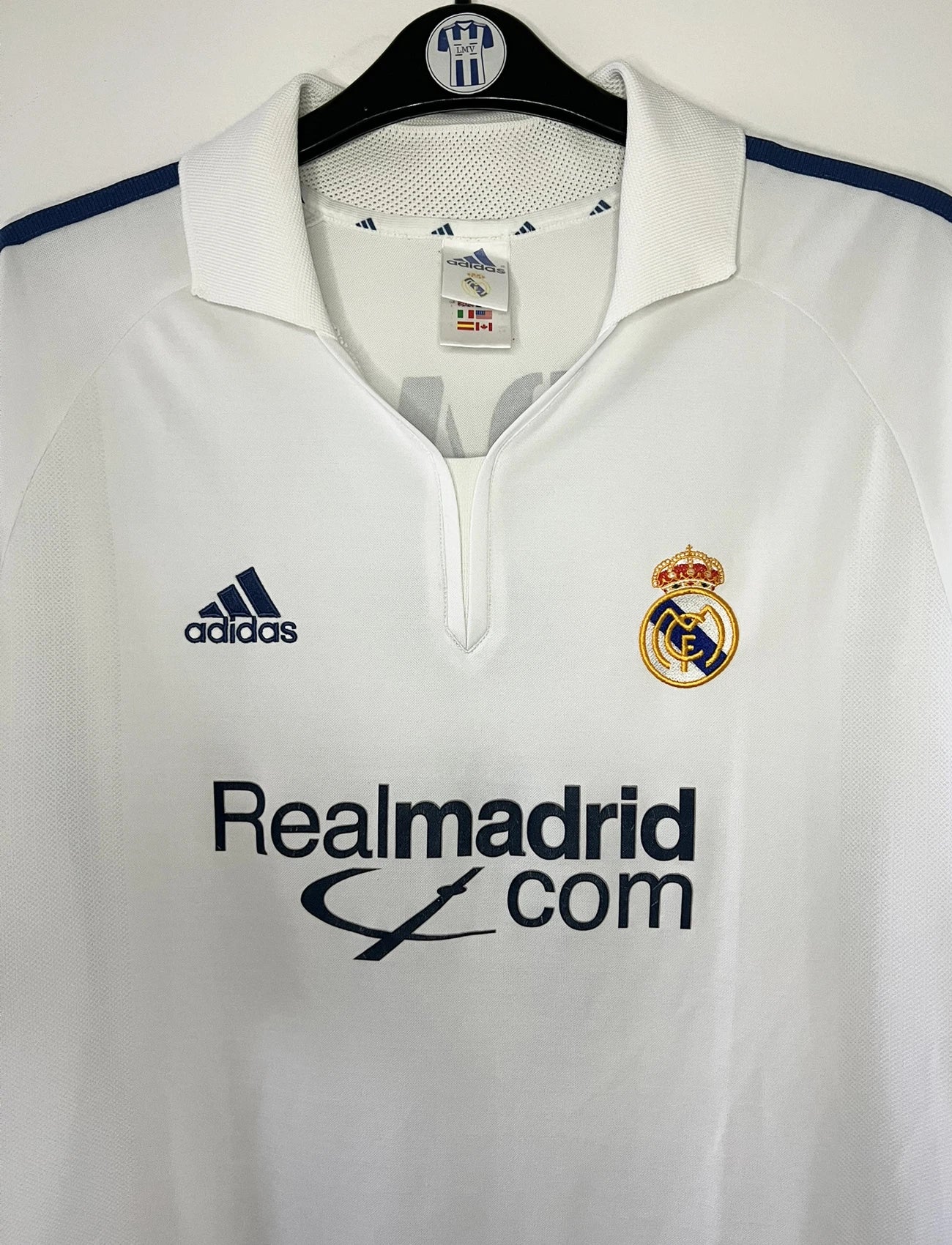 Maillot de foot vintage domicile du real madrid de la saison 2001-2002. Le maillot est de couleur blanc et noir. On peut retrouver l'équipementier adidas et le sponsor Real Madrid.com. Le maillot est floqué du numéro 5 Zinedine Zidane. Il s'agit d'un maillot authentique comportant les numéros 695856