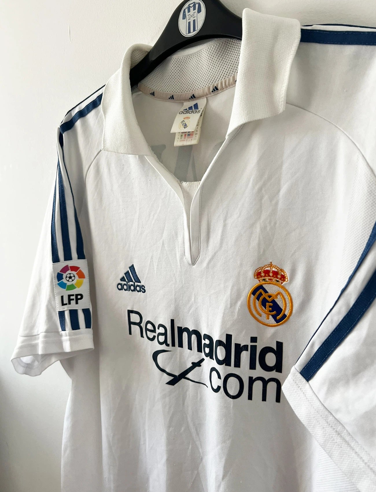 Maillot de foot vintage domicile blanc du real madrid de la saison 2001/2002. On peut retrouver l'équipementier Adidas et le sponsor Real madrid.com. Le maillot est floqué du numéro 5 Zinedine Zidane. Il s'agit d'un maillot authentique d'époque.