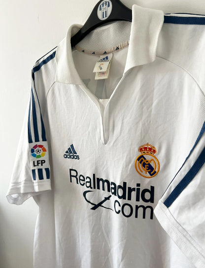 Maillot de foot vintage domicile blanc du real madrid de la saison 2001/2002. On peut retrouver l'équipementier Adidas et le sponsor Real madrid.com. Le maillot est floqué du numéro 5 Zinedine Zidane. Il s'agit d'un maillot authentique d'époque.