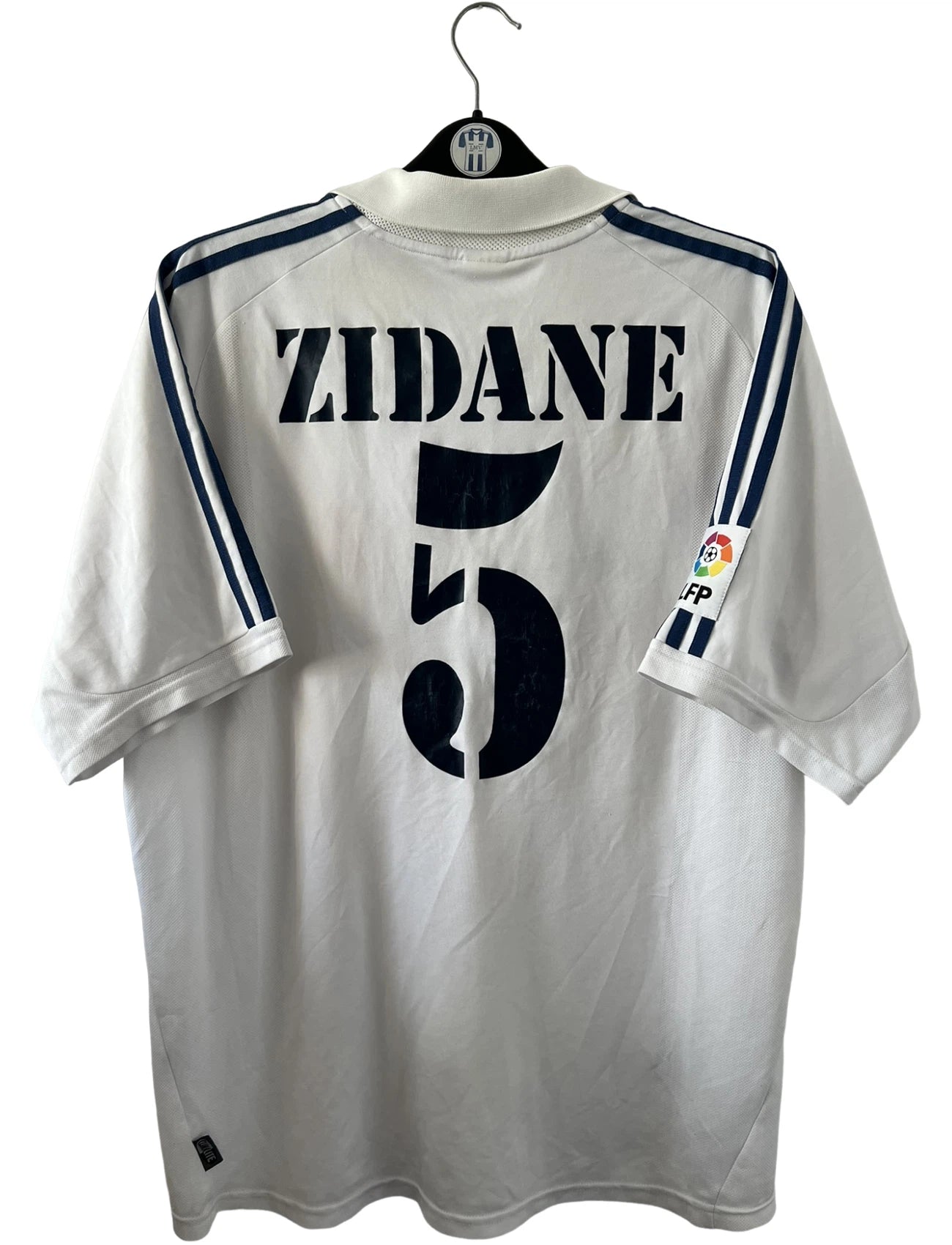 Maillot de foot vintage domicile blanc du real madrid de la saison 2001/2002. On peut retrouver l'équipementier Adidas et le sponsor Real madrid.com. Le maillot est floqué du numéro 5 Zinedine Zidane. Il s'agit d'un maillot authentique d'époque.