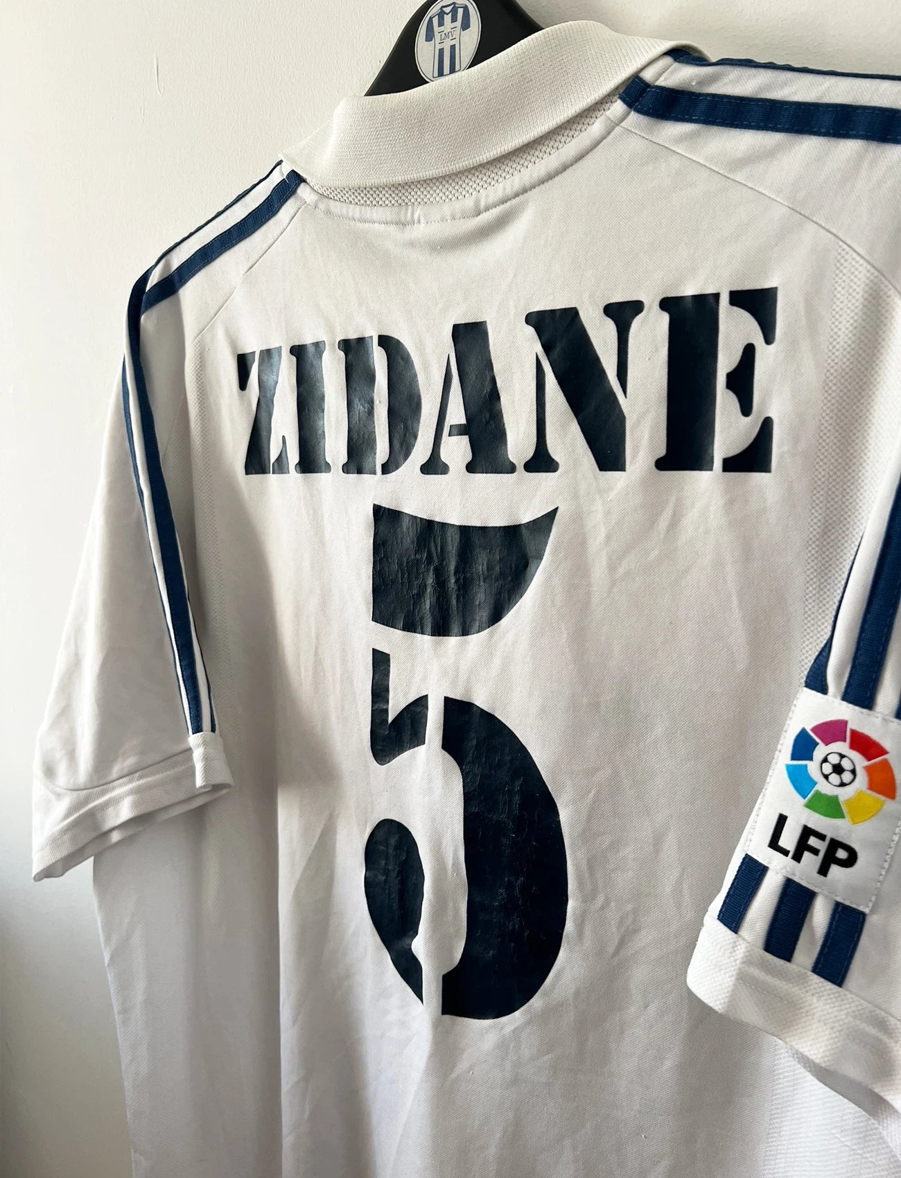 Maillot de foot vintage domicile blanc du real madrid de la saison 2001/2002. On peut retrouver l'équipementier Adidas et le sponsor Real madrid.com. Le maillot est floqué du numéro 5 Zinedine Zidane. Il s'agit d'un maillot authentique d'époque.