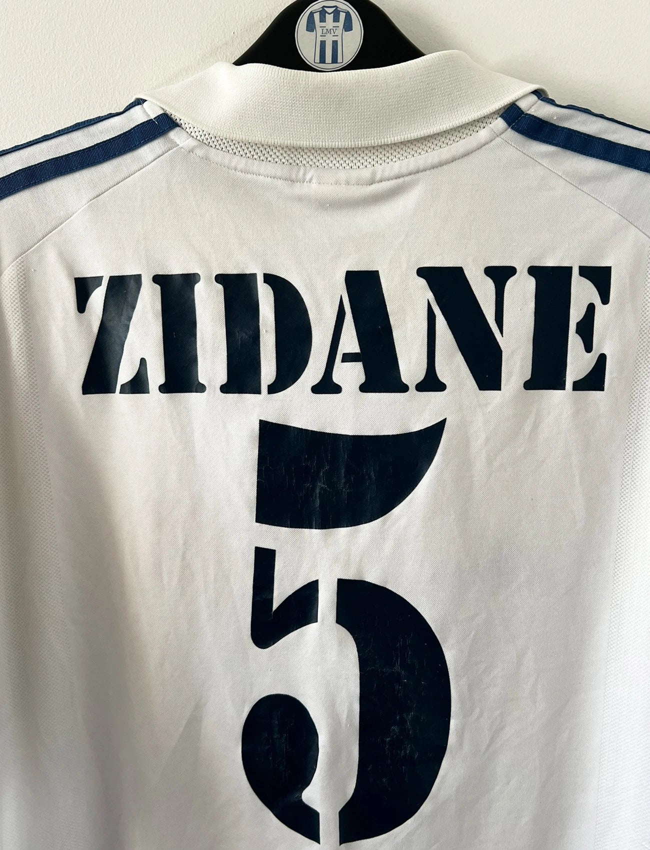 Maillot de foot vintage domicile blanc du real madrid de la saison 2001/2002. On peut retrouver l'équipementier Adidas et le sponsor Real madrid.com. Le maillot est floqué du numéro 5 Zinedine Zidane. Il s'agit d'un maillot authentique d'époque.