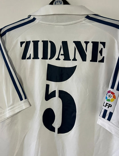 Maillot de foot vintage domicile blanc du real madrid de la saison 2001/2002. On peut retrouver l'équipementier Adidas et le sponsor Real madrid.com. Le maillot est floqué du numéro 5 Zinedine Zidane. Il s'agit d'un maillot authentique d'époque.