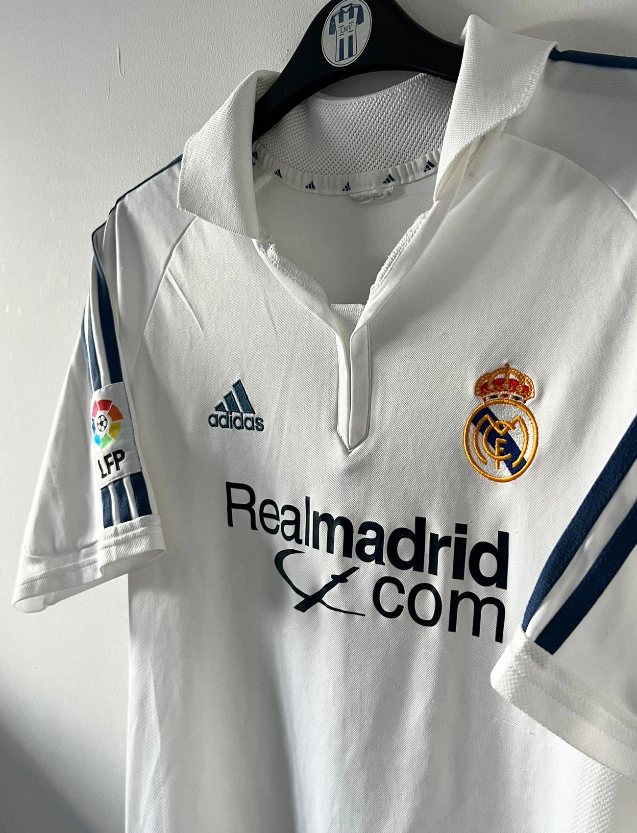 Maillot de foot vintage domicile blanc du real madrid de la saison 2001/2002. On peut retrouver l'équipementier Adidas et le sponsor Real Madrid.com. Le maillot est floqué du numéro 5 Zinedine Zidane. Il s'agit d'un maillot authentique d'époque.