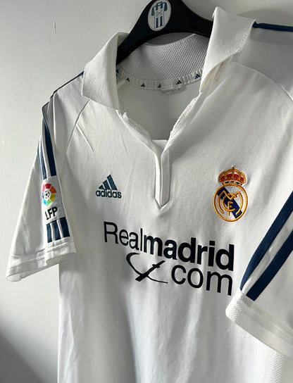 Maillot de foot vintage domicile blanc du real madrid de la saison 2001/2002. On peut retrouver l'équipementier Adidas et le sponsor Real Madrid.com. Le maillot est floqué du numéro 5 Zinedine Zidane. Il s'agit d'un maillot authentique d'époque.