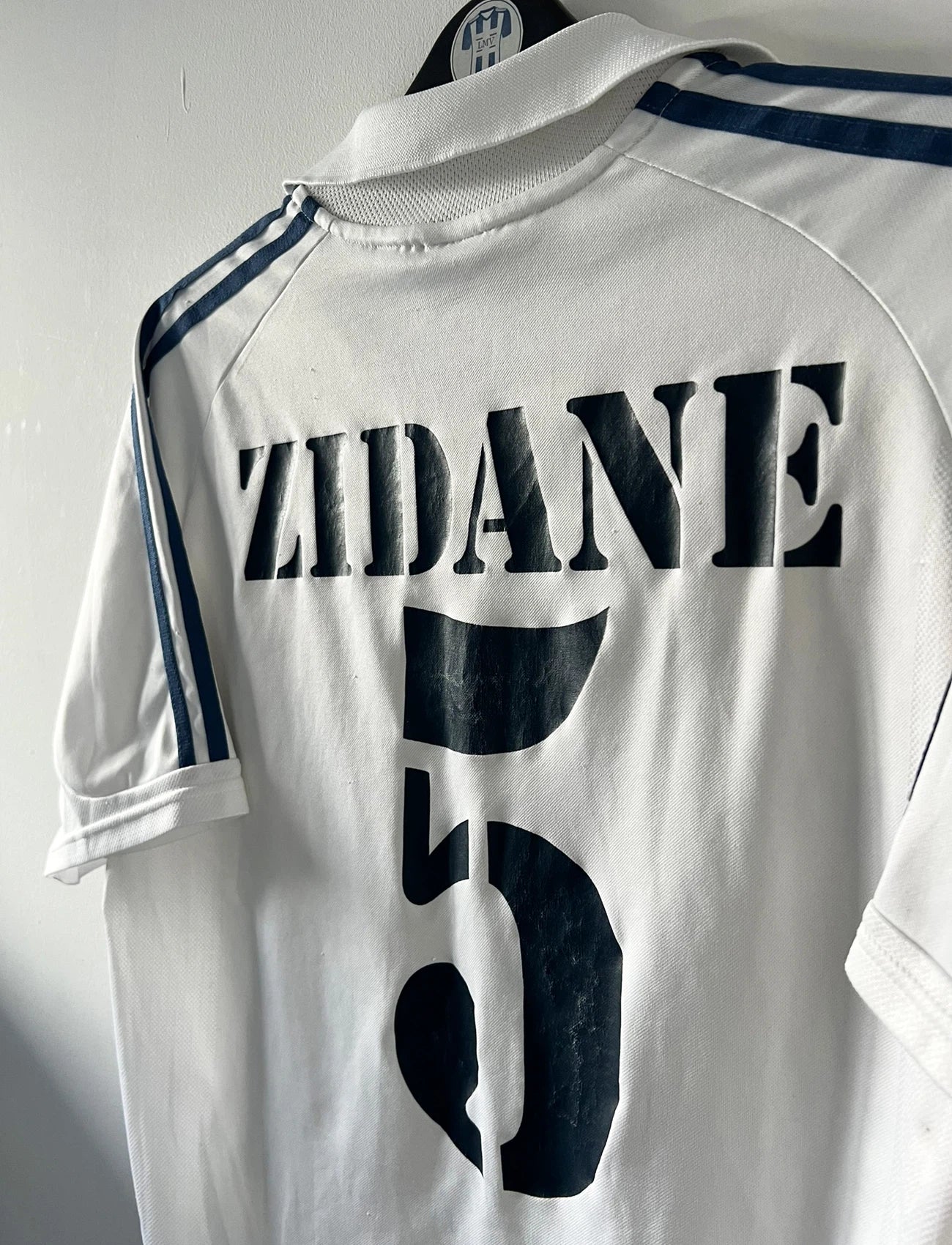 Maillot de foot vintage domicile blanc du real madrid de la saison 2001/2002. On peut retrouver l'équipementier Adidas et le sponsor Real Madrid.com. Le maillot est floqué du numéro 5 Zinedine Zidane. Il s'agit d'un maillot authentique d'époque.