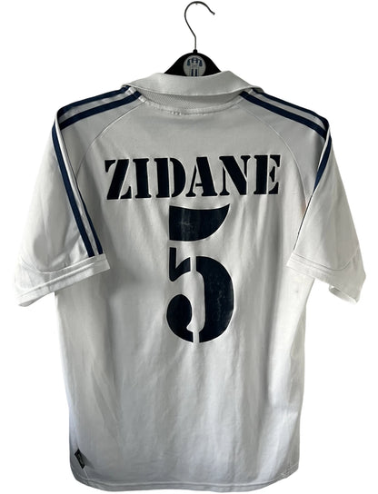 Maillot de foot vintage domicile blanc du real madrid de la saison 2001/2002. On peut retrouver l'équipementier Adidas et le sponsor Real Madrid.com. Le maillot est floqué du numéro 5 Zinedine Zidane. Il s'agit d'un maillot authentique d'époque.