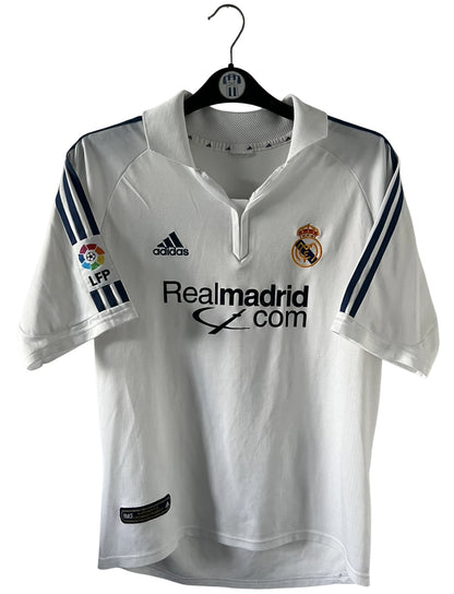 Maillot de foot vintage domicile blanc du real madrid de la saison 2001/2002. On peut retrouver l'équipementier Adidas et le sponsor Real Madrid.com. Le maillot est floqué du numéro 5 Zinedine Zidane. Il s'agit d'un maillot authentique d'époque.
