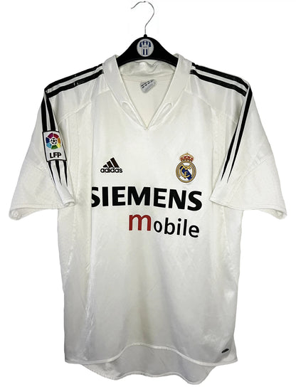 Maillot de foot vintage domicile blanc du real madrid de la saison 2004/2005. On peut retrouver l'équipementier Adidas et le sponsor Siemens. Il s'agit d'un maillot authentique d'époque comportant l'étiquette 367842