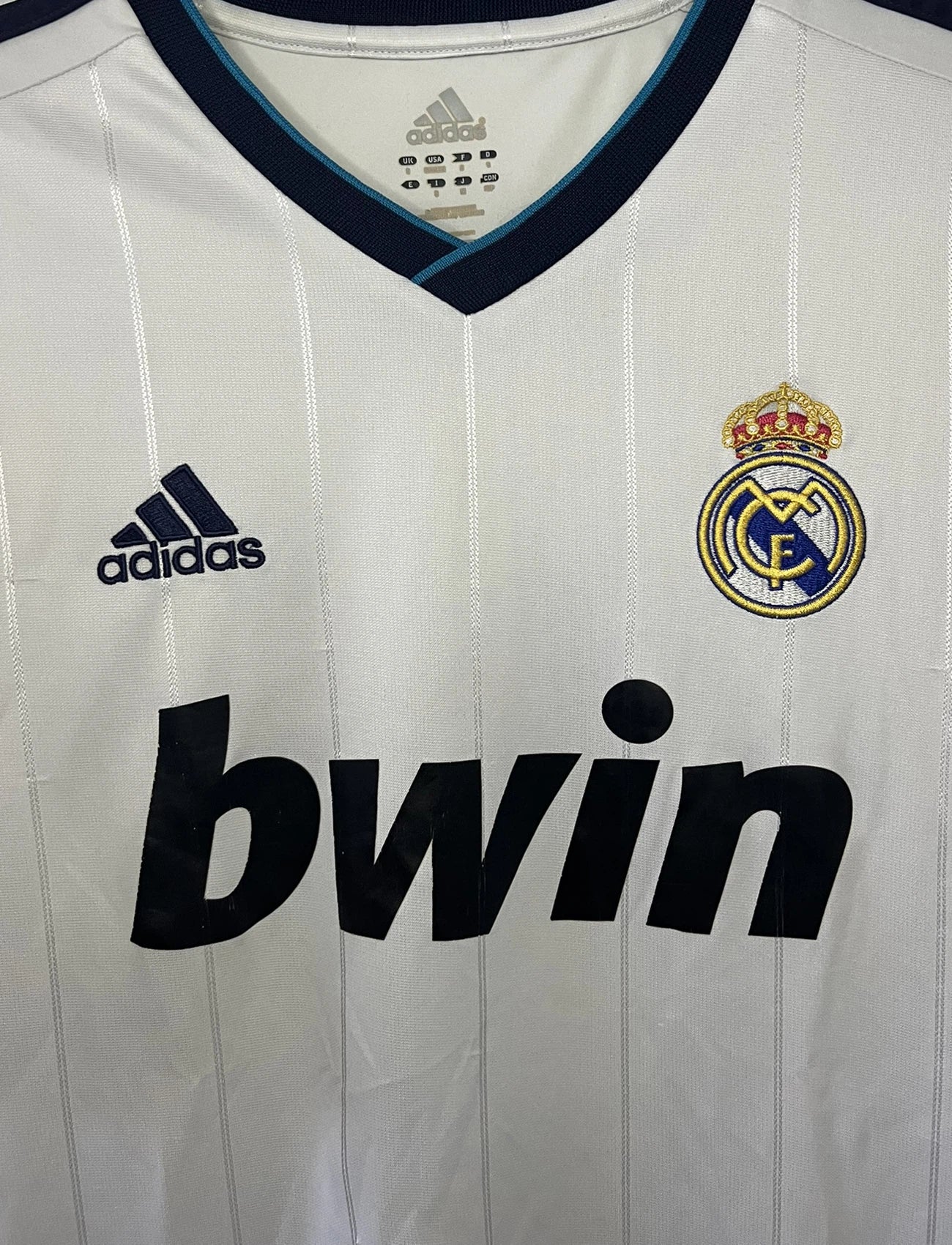 Maillot de foot vintage domicile blanc du real madrid de la saison 2012/2013. On peut retrouver l'équipementier adidas et le sponsor bwin. Le maillot est floqué du numéro 7 Cristiano Ronaldo. Il s'agit d'un maillot authentique comportant les numéros X21987.