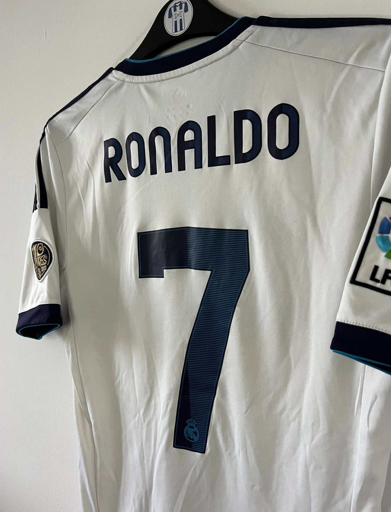 Maillot de foot vintage domicile blanc du real madrid de la saison 2012/2013. On peut retrouver l'équipementier adidas et le sponsor bwin. Le maillot est floqué du numéro 7 Cristiano Ronaldo. Il s'agit d'un maillot authentique comportant les numéros X21987.