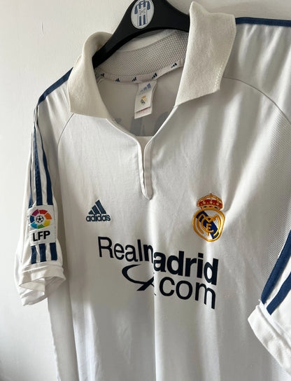 Maillot de foot vintage domicile blanc du Real Madrid de la saison 2001/2002. On peut retrouver l'équipementier Adidas et le sponsor Real Madrid.com. Le maillot est floqué du numéro 5 Zinedine Zidane. Il s'agit d'un maillot authentique d'époque.