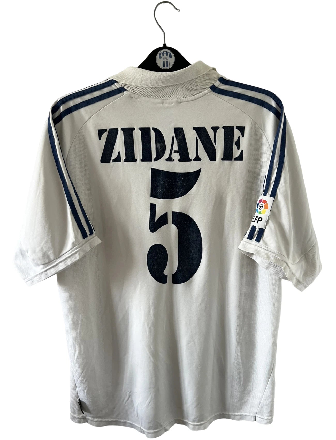 Maillot de foot vintage domicile blanc du Real Madrid de la saison 2001/2002. On peut retrouver l'équipementier Adidas et le sponsor Real Madrid.com. Le maillot est floqué du numéro 5 Zinedine Zidane. Il s'agit d'un maillot authentique d'époque.