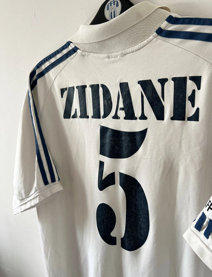 Maillot de foot vintage domicile blanc du Real Madrid de la saison 2001/2002. On peut retrouver l'équipementier Adidas et le sponsor Real Madrid.com. Le maillot est floqué du numéro 5 Zinedine Zidane. Il s'agit d'un maillot authentique d'époque.