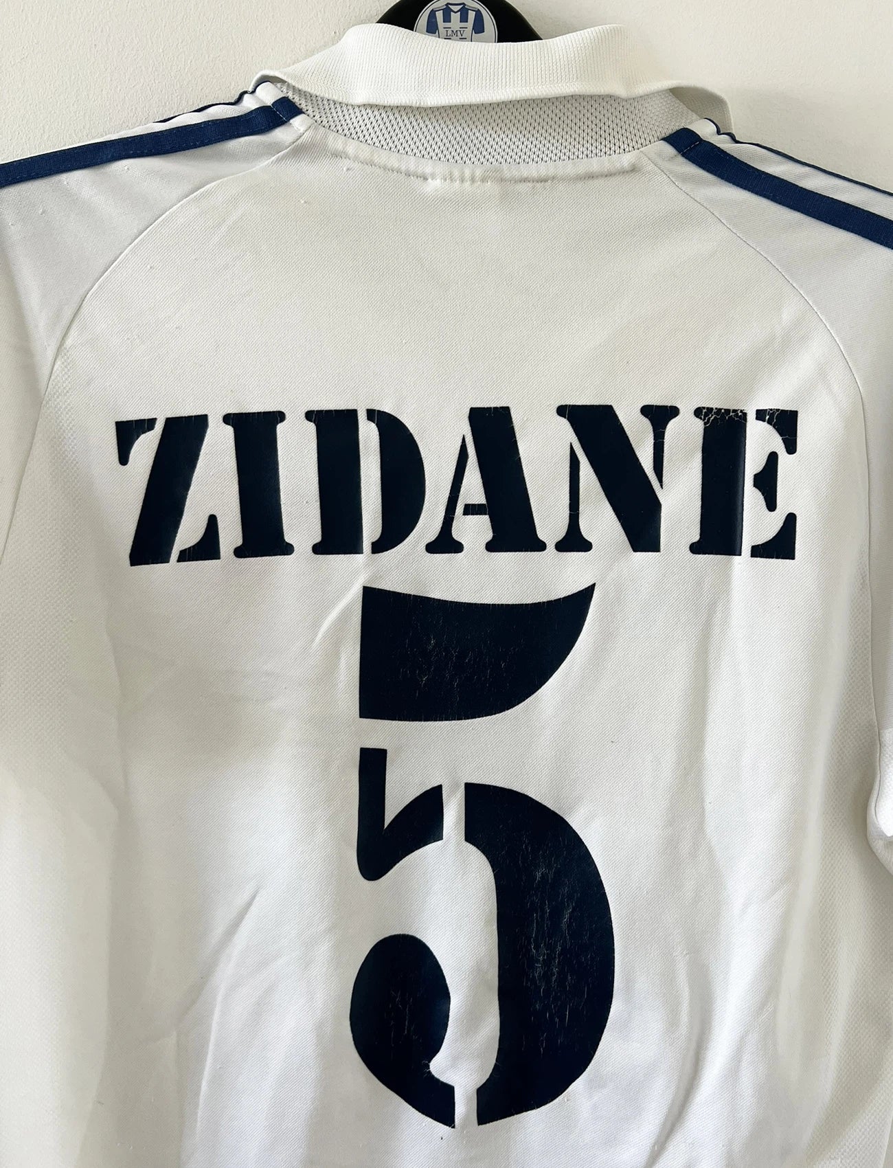 Maillot de foot vintage domicile blanc du real madrid de la saison 2001/2002. On peut retrouver l'équipementier Adidas et le sponsor Rea Madrid. Le maillot est floqué du numéro 5 Zinedine Zidane. Il s'agit d'un maillot authentique d'époque.