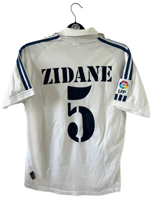 Maillot de foot vintage domicile blanc du real madrid de la saison 2001/2002. On peut retrouver l'équipementier Adidas et le sponsor Rea Madrid. Le maillot est floqué du numéro 5 Zinedine Zidane. Il s'agit d'un maillot authentique d'époque.