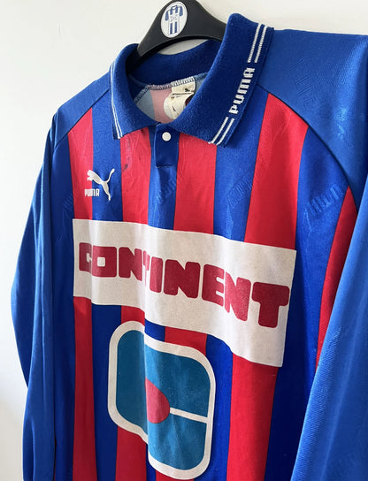 Maillot de foot vintage domicile rouge et bleu du SM Caen de la saison 1994/1995. On peut retrouver l'équipementier Puma et le sponsor Continent. Le maillot est floqué du numéro 9 Kennet Andersson. Il s'agit d'un maillot authentique d'époque.