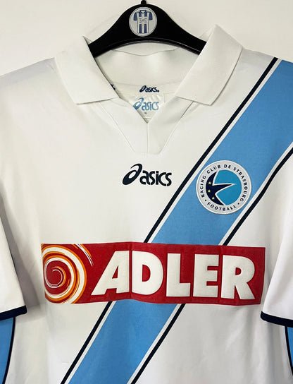 Maillot de foot vintage extérieur blanc du Racing Club de Strasbourg de la saison 2001/2003. On peut retrouver l'équipementier Asics et le sponsor Adler. Il s'agit d'un maillot authentique d'époque.