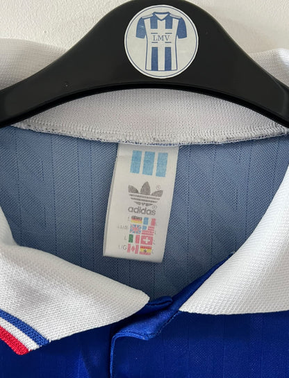 Maillot de foot vintage domicile bleu de l'Equipe de France 1994. On peut retrouver l'équipementier Adidas. Il s'agit d'un maillot authentique d'époque.