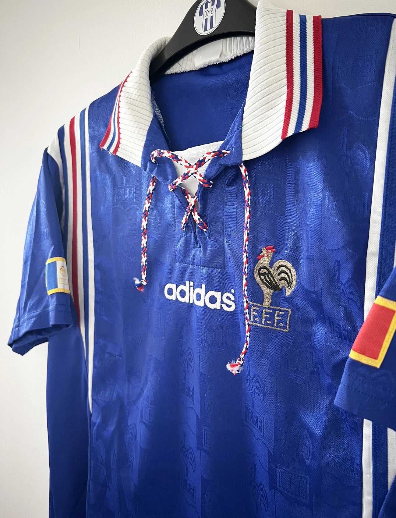 Maillot de foot vintage domicile de l'équipe de france 1996 de couleur bleu blanc et rouge. On peut retrouver l'équipementier adidas et le coq sans étoile. Il s'agit d'un maillot authentique d'époque.
