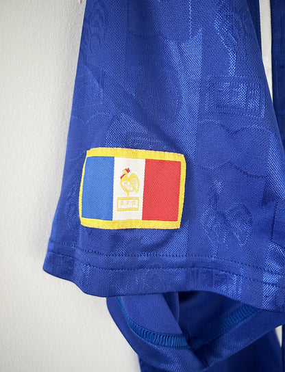 Maillot de foot vintage domicile bleu blanc et rouge de l'équipe de france 1996. On peut retrouver l'équipementier adidas. Il s'agit d'un maillot authentique d'époque