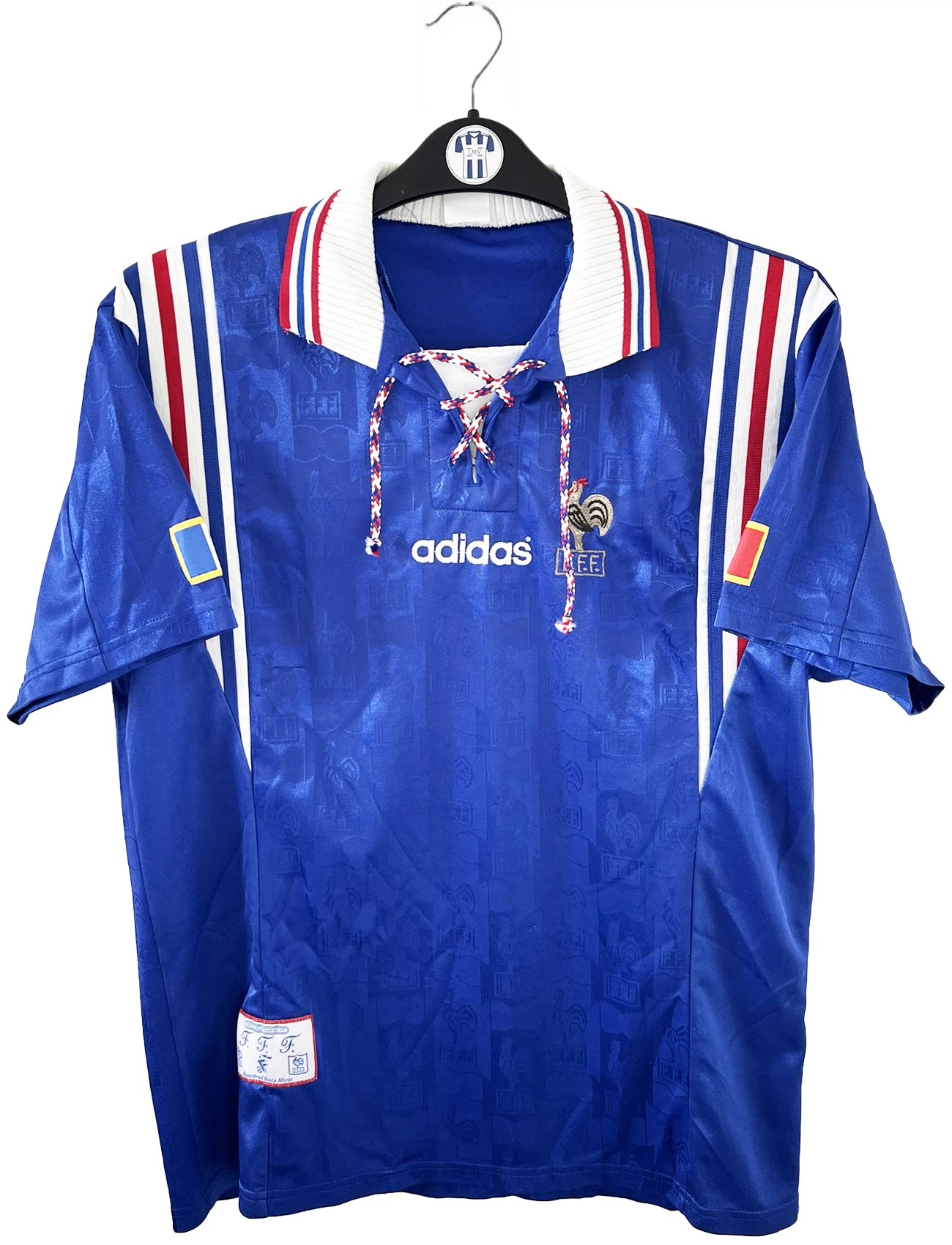 Maillot de foot vintage domicile de l'équipe de france 1996 de couleur bleu blanc et rouge. On peut retrouver l'équipementier adidas et le coq sans étoile. Il s'agit d'un maillot authentique d'époque.