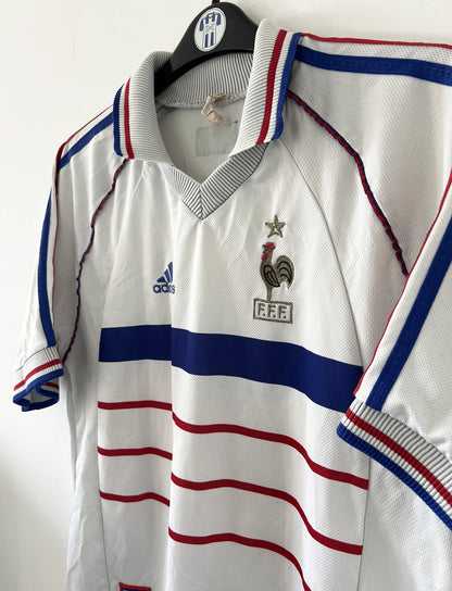 Maillot de foot vintage extérieur blanc de l'Equipe de France 1998. On peut retrouver l'équipementier Adidas. Il s'agit d'un maillot authentique d'époque.