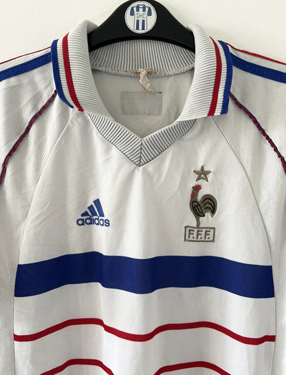 Maillot de foot vintage extérieur blanc de l'Equipe de France 1998. On peut retrouver l'équipementier Adidas. Il s'agit d'un maillot authentique d'époque.