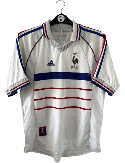 Maillot de foot vintage extérieur blanc de l'Equipe de France 1998. On peut retrouver l'équipementier Adidas. Il s'agit d'un maillot authentique d'époque.