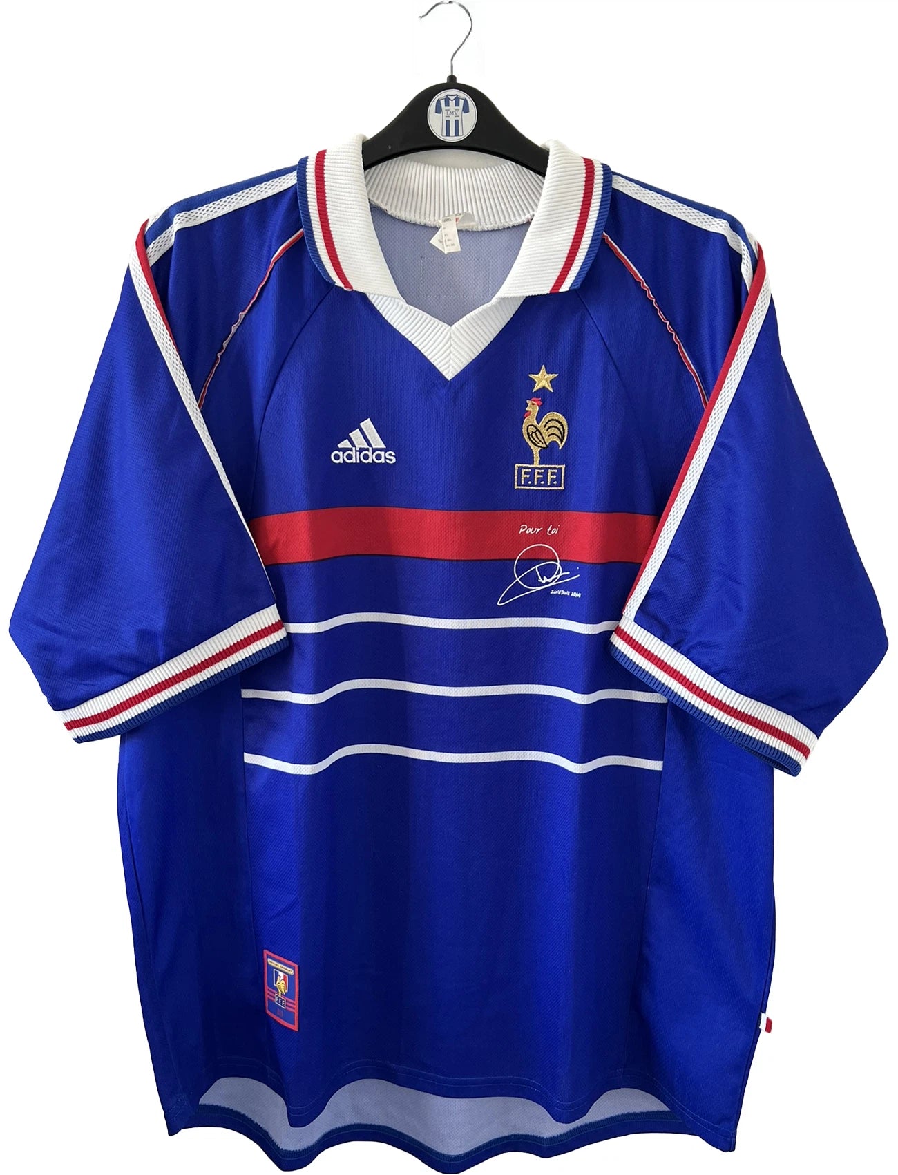 Maillot de foot vintage bleu blanc et rouge domicile de l'équipe de France 1998. On peut retrouver le sponsor adidas. On peut voir le coq sans l'étoile avec la signature "pour toi" de Zinedine Zidane. Il s'agit d'un maillot authentique.