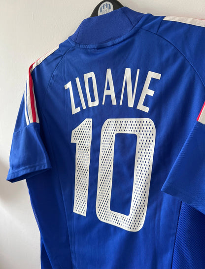 Maillot de foot vintage domicile bleu de l'équipe de france 2002. On peut retrouver l'équipementier Adidas. Le maillot est floqué du numéro 10 Zidane. Il s'agit d'un maillot authentique d'époque.