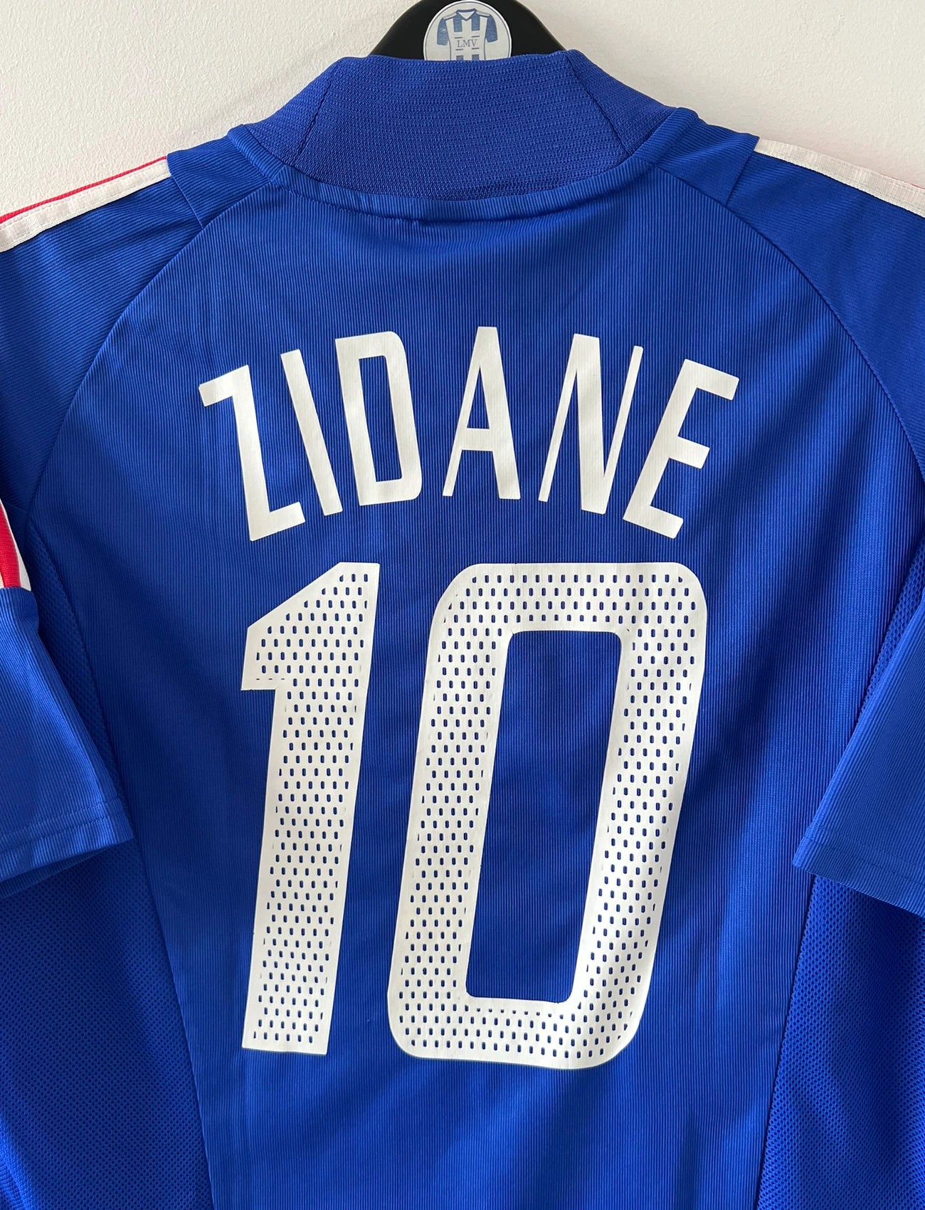 Maillot de foot vintage domicile bleu de l'équipe de france 2002. On peut retrouver l'équipementier Adidas. Le maillot est floqué du numéro 10 Zidane. Il s'agit d'un maillot authentique d'époque.