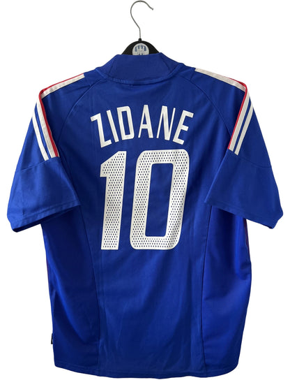 Maillot de foot vintage domicile bleu de l'équipe de france 2002. On peut retrouver l'équipementier Adidas. Le maillot est floqué du numéro 10 Zidane. Il s'agit d'un maillot authentique d'époque.