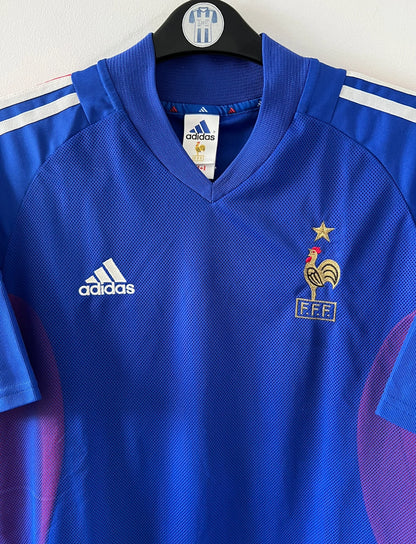 Maillot de foot vintage domicile bleu de l'équipe de france 2002. On peut retrouver l'équipementier Adidas. Le maillot est floqué du numéro 10 Zidane. Il s'agit d'un maillot authentique d'époque.