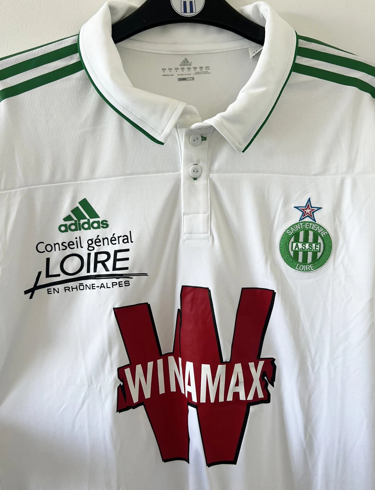 Maillot de foot vintage extérieur blanc et vert de l'ASSE de l'année 2010/2011. On peut retrouver l'équipementier adidas et le sponsor Winamax. Il s'agit d'un maillot authentique d'époque comportant les numéros U40897
