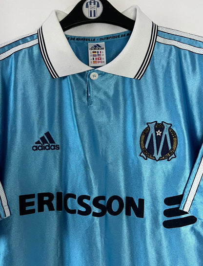 Maillot de foot vintage extérieur bleu de l'OM saison 1998/1999. On peut retrouver l'équipementier Adidas et le sponsor Ericsson. Il s'agit d'un maillot authentique d'époque.