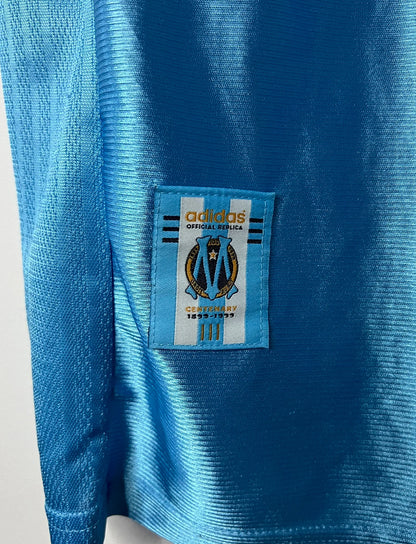 Maillot de foot vintage extérieur bleu de l'OM saison 1998/1999. On peut retrouver l'équipementier Adidas et le sponsor Ericsson. Il s'agit d'un maillot authentique d'époque.