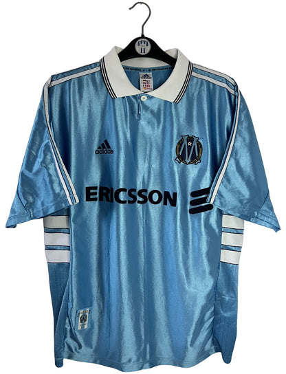 Maillot de foot vintage extérieur bleu de l'OM saison 1998/1999. On peut retrouver l'équipementier Adidas et le sponsor Ericsson. Il s'agit d'un maillot authentique d'époque.