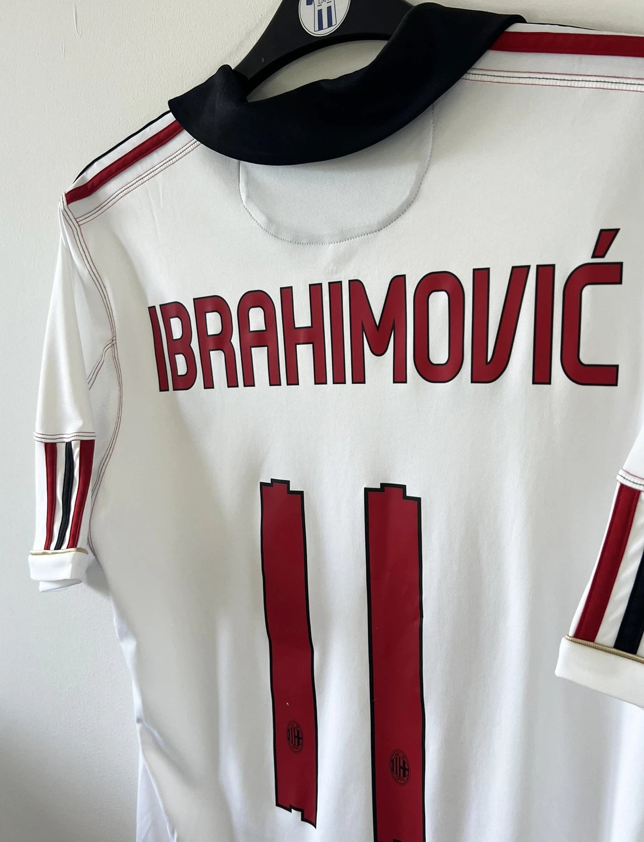 Maillot de foot vintage extérieur de l'AC Milan couleur blanc de la saison 2010/2011. On peut retrouver l'équipementier adidas et le sponsor Fly Emirates. Le maillot est floqué du numéro 11 Zlatan Ibrahimovic. Il s'agit d'un maillot authentique d'époque comportant les numéros P96277
