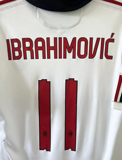 Maillot de foot vintage extérieur de l'AC Milan couleur blanc de la saison 2010/2011. On peut retrouver l'équipementier adidas et le sponsor Fly Emirates. Le maillot est floqué du numéro 11 Zlatan Ibrahimovic. Il s'agit d'un maillot authentique d'époque comportant les numéros P96277