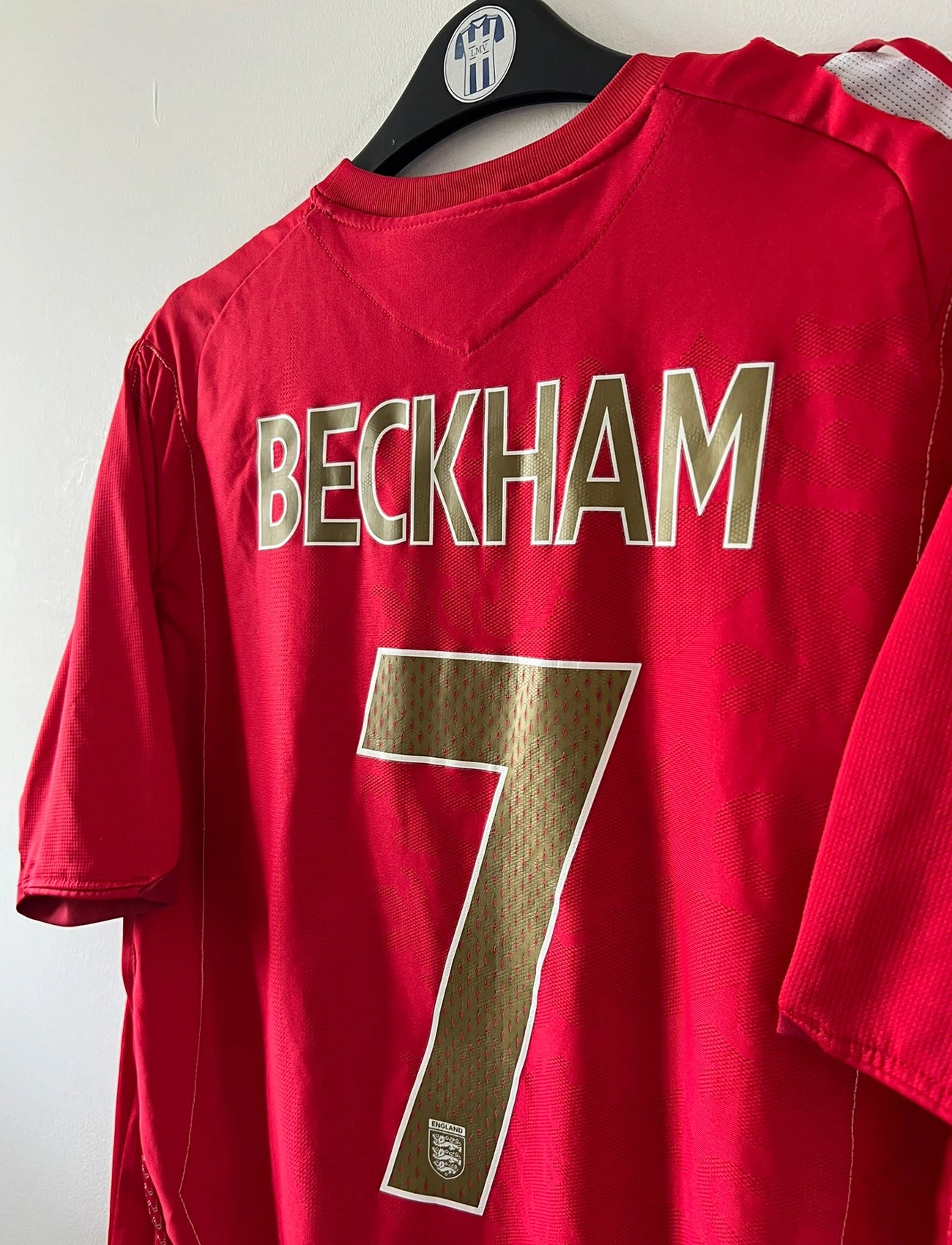 Maillot de foot vintage extérieur rouge de l'angleterre 2006/2008. On peut retrouver l'équipementier Umbro. Le maillot est floqué du numéro 7 David Beckham. Il s'agit d'un maillot authentique d'époque.