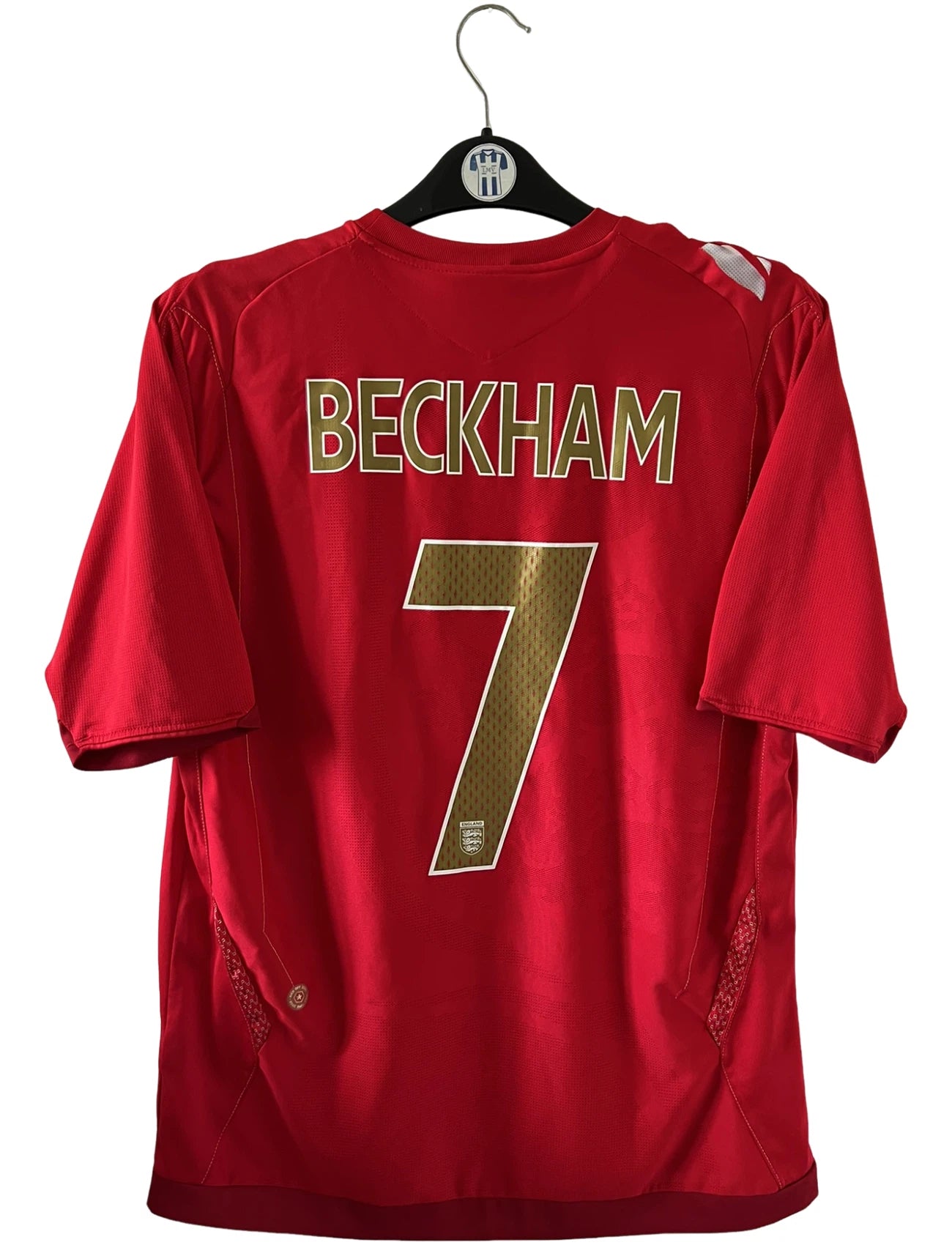 Maillot de foot vintage extérieur rouge de l'angleterre 2006/2008. On peut retrouver l'équipementier Umbro. Le maillot est floqué du numéro 7 David Beckham. Il s'agit d'un maillot authentique d'époque.