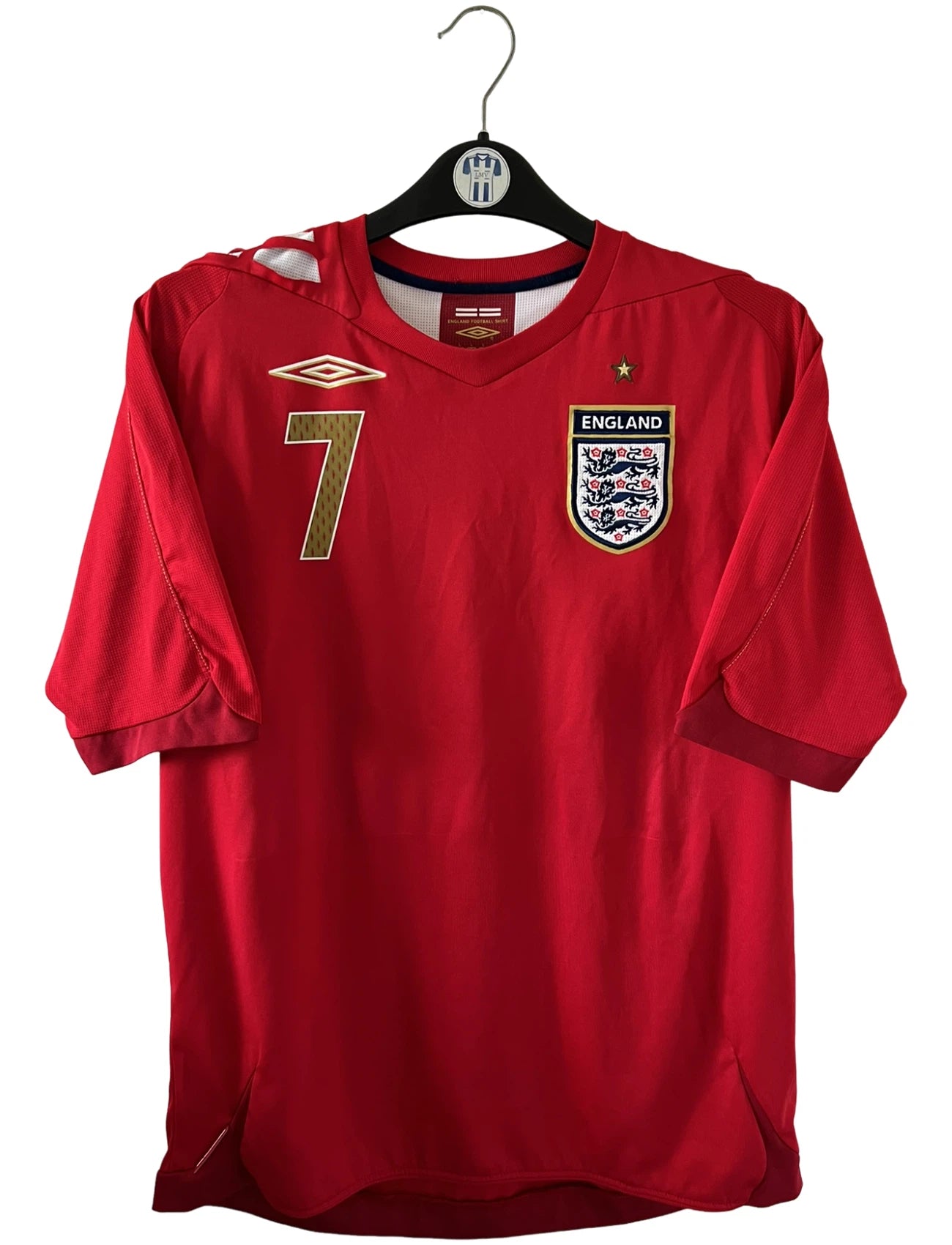 Maillot de foot vintage extérieur rouge de l'angleterre 2006/2008. On peut retrouver l'équipementier Umbro. Le maillot est floqué du numéro 7 David Beckham. Il s'agit d'un maillot authentique d'époque.