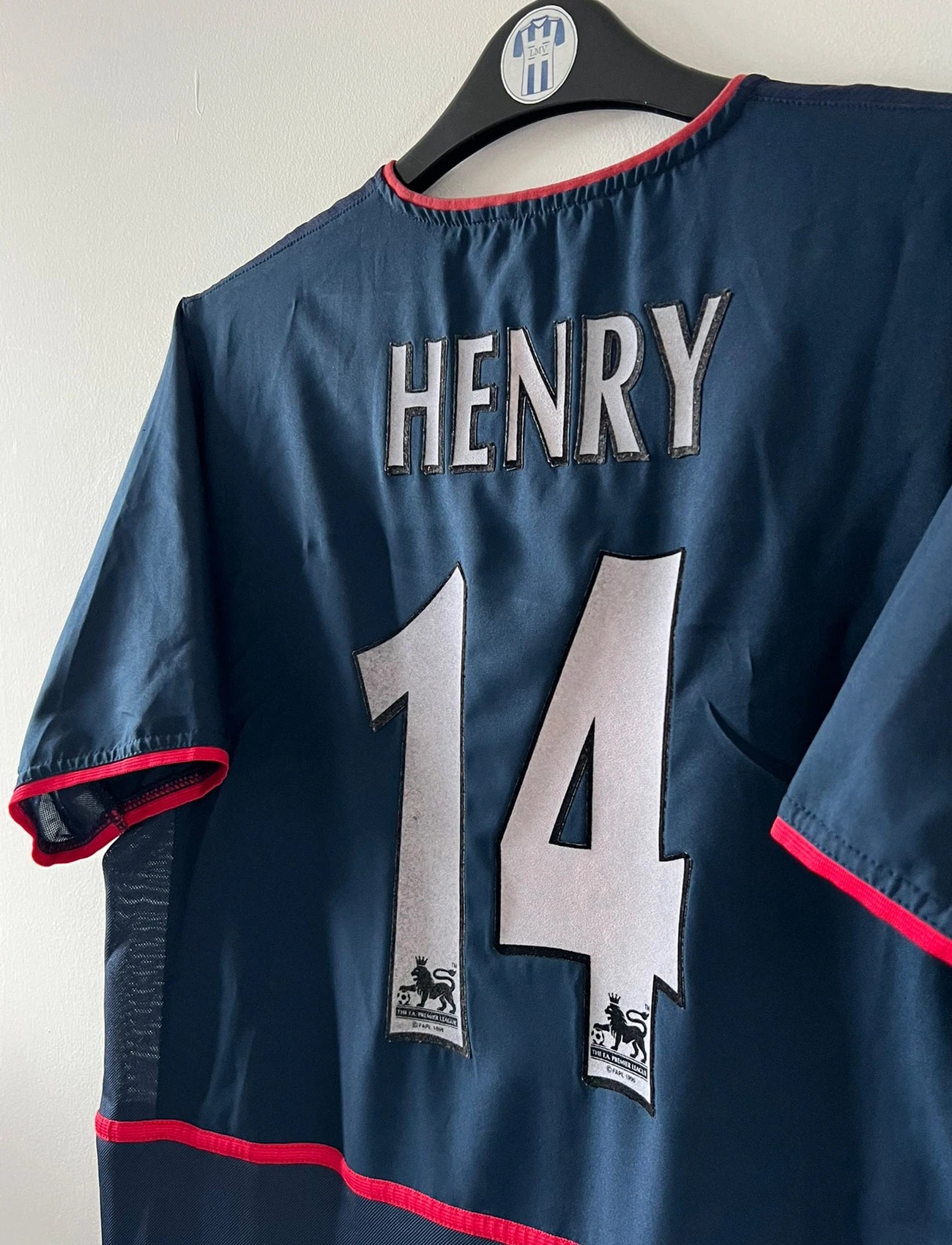 Maillot foot vintage extérieur bleu d'arsenal de la saison 2002/2003. On peut retrouver l'équipementier Nike et le sponsor O2. Le maillot est floqué du numéro 14 Thierry Henry. Il s'agit d'un maillot authentique d'époque. 