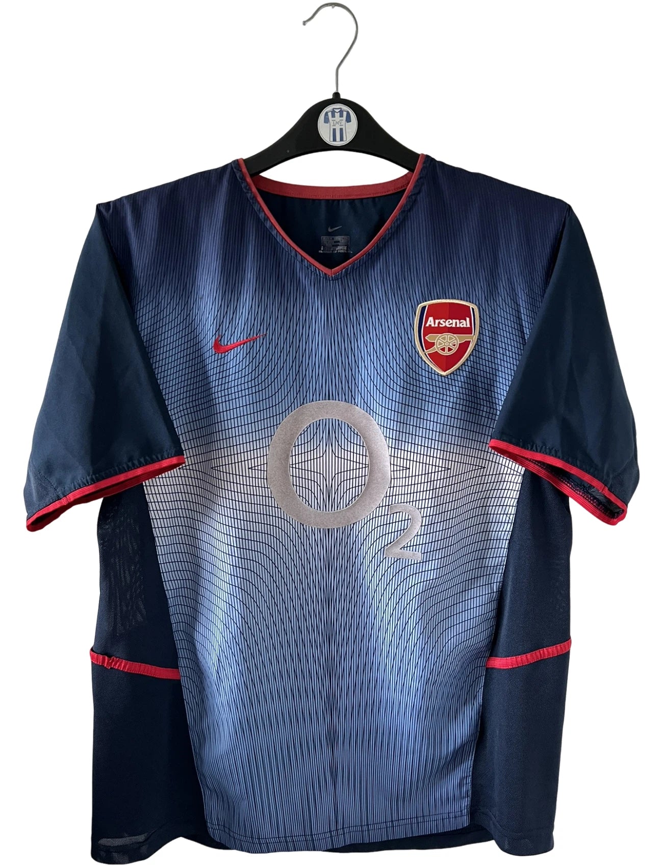 Maillot foot vintage extérieur bleu d'arsenal de la saison 2002/2003. On peut retrouver l'équipementier Nike et le sponsor O2. Le maillot est floqué du numéro 14 Thierry Henry. Il s'agit d'un maillot authentique d'époque. 