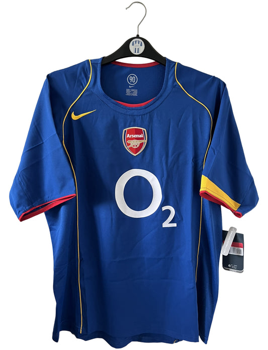 Maillot de foot vintage extérieur bleu d'Arsenal de la saison 2004/2005. On peut retrouver l'équipementier Nike et le sponsor O2. Il s'agit d'un maillot authentique d'époque.