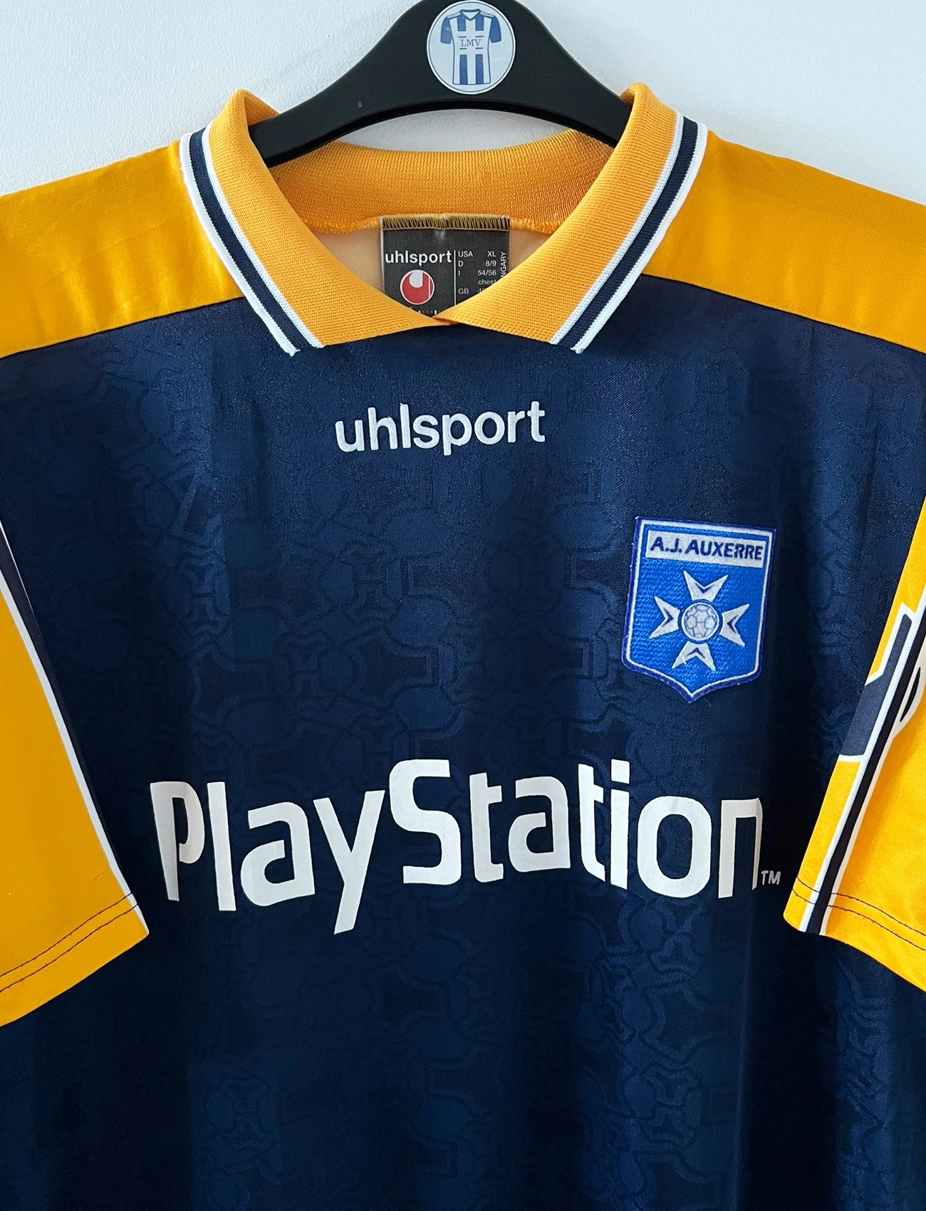 Maillot de foot vintage extérieur jaune et bleu de l'AJ Auxerre 2000/2001. On peut retrouver l'équipementier Uhlsport et le sponsor Playstation. Il s'agit d'un maillot authentique d'époque.